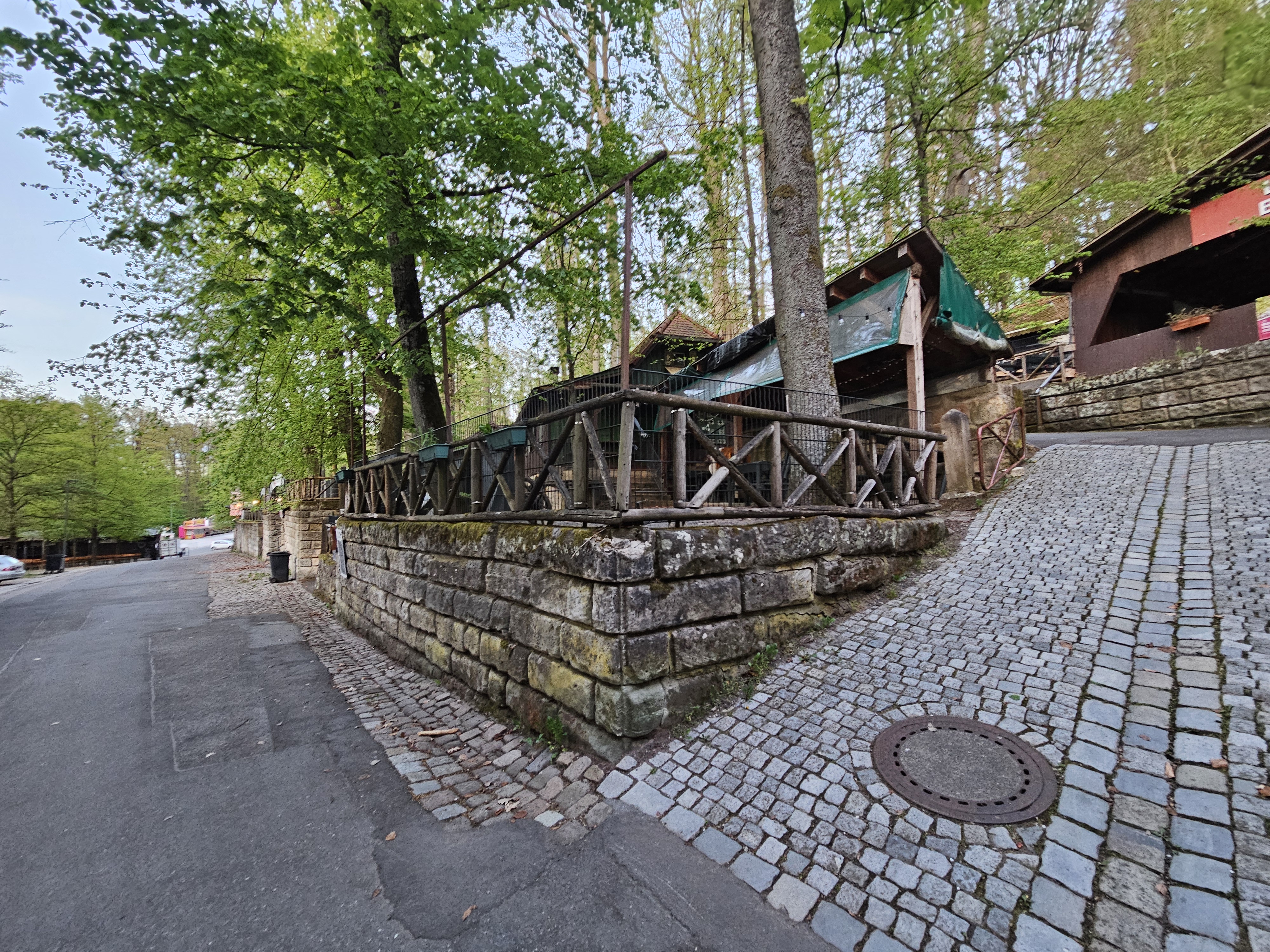 Rappenkeller-Ansicht vom Hauptweg mit Sandsteinmauer und überdachten Sitzplätzen im Forchheimer Kellerwald.