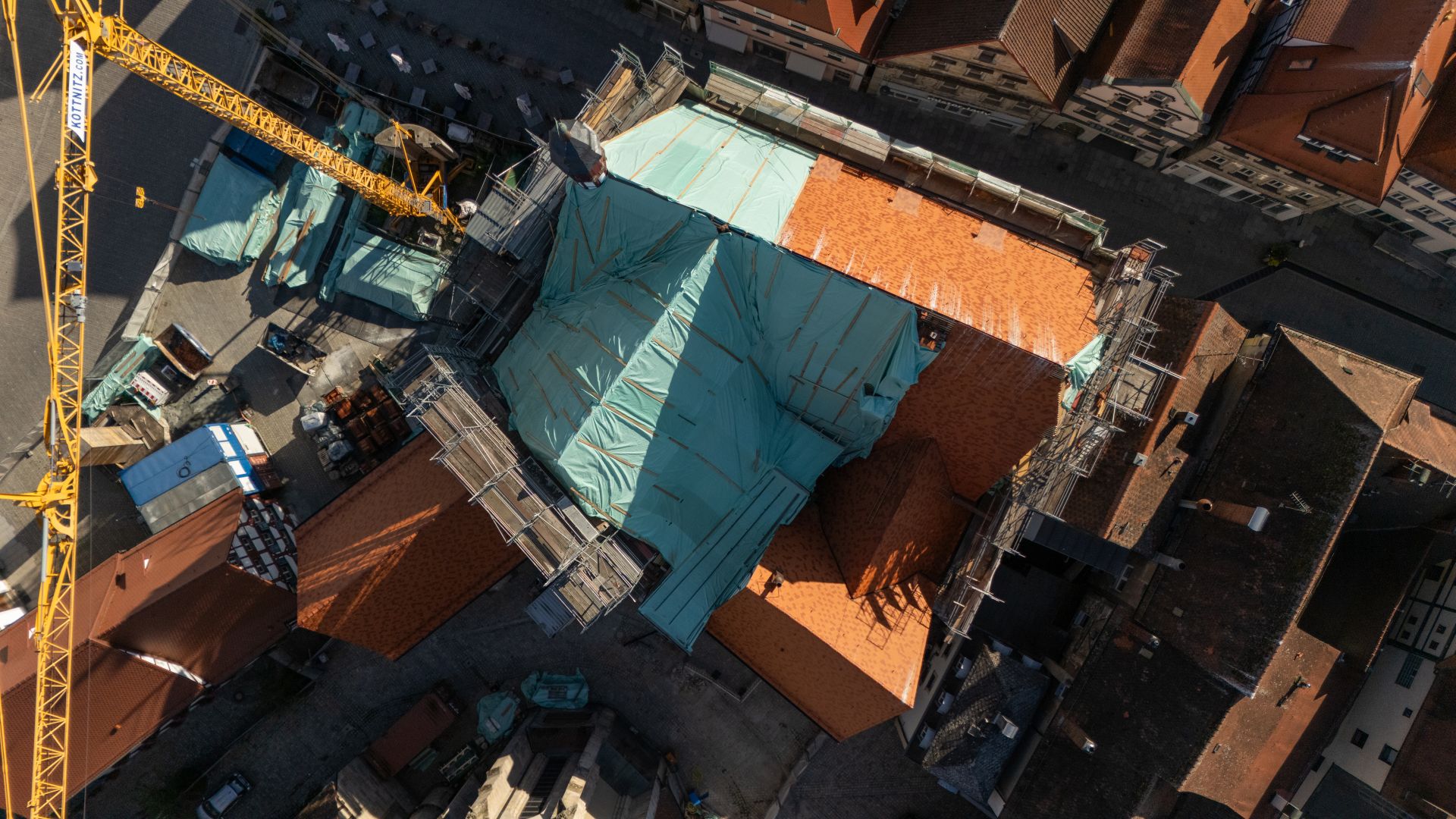 Fortgeschrittene Dachdeckungsarbeiten am Bauteil A Fortgeschrittene Dachdeckungsarbeiten am historischen Rathaus in Forchheim aus der Vogelperspektive. Das Dach ist teilweise mit Wetterschutzplanen noch abgedeckt. Links im Bild ist der Baustellenkran zu sehen.