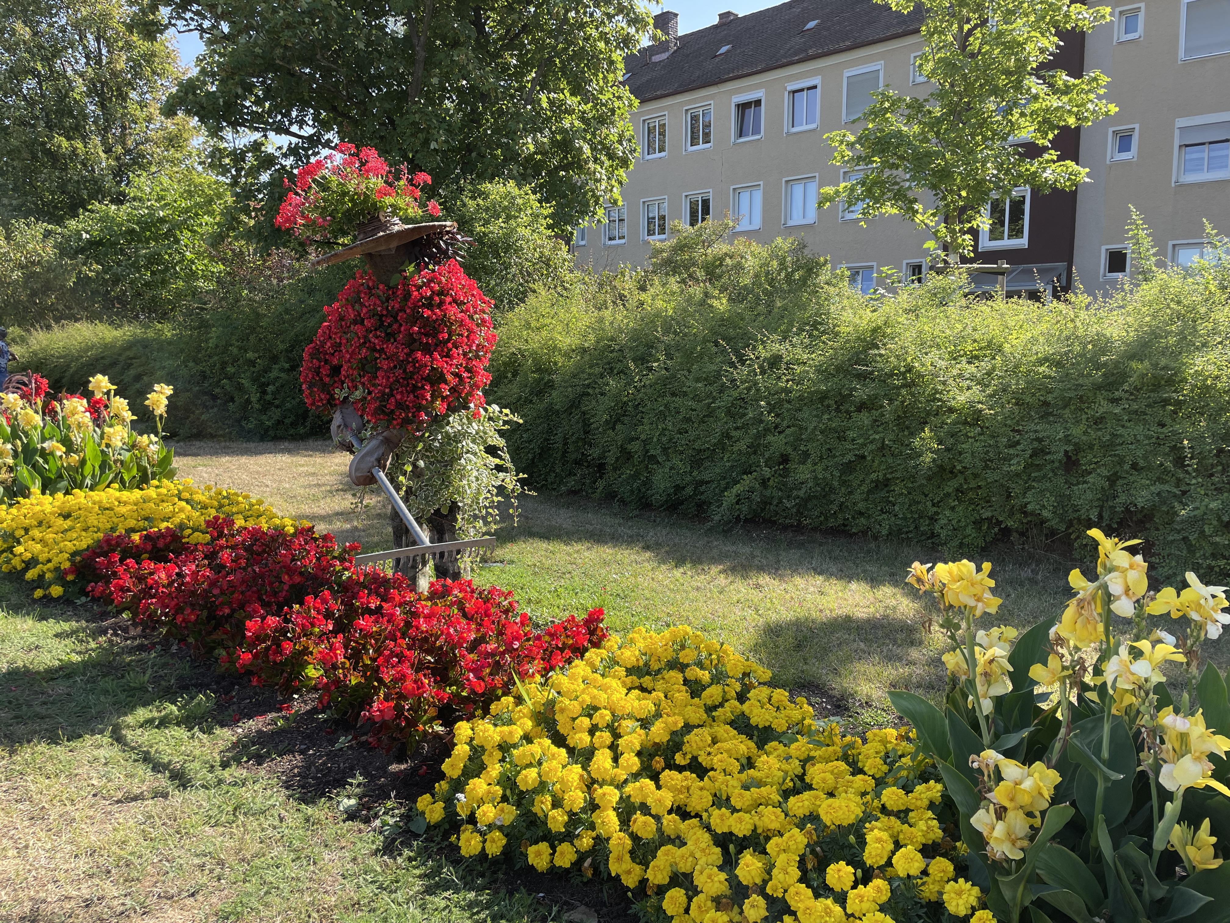 Buntes Sommerblumenbeet mit einer bepflanzten Figur, die einen Gärtner darstellen soll.