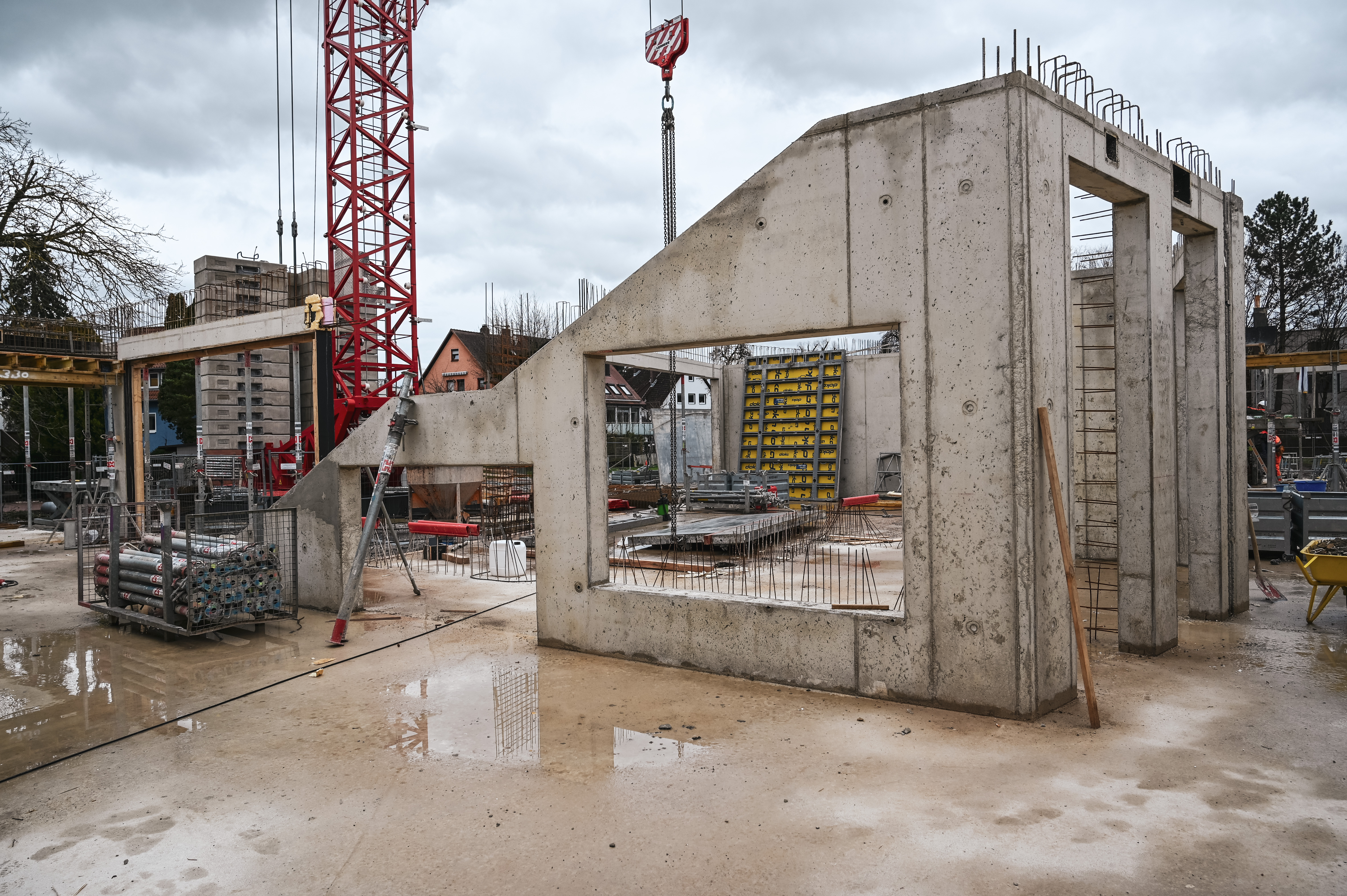 Die Betonwände werden im Erdgeschoss eines Rohbaus errichtet. In der Mitte befindet sich ein Baustellenkran.