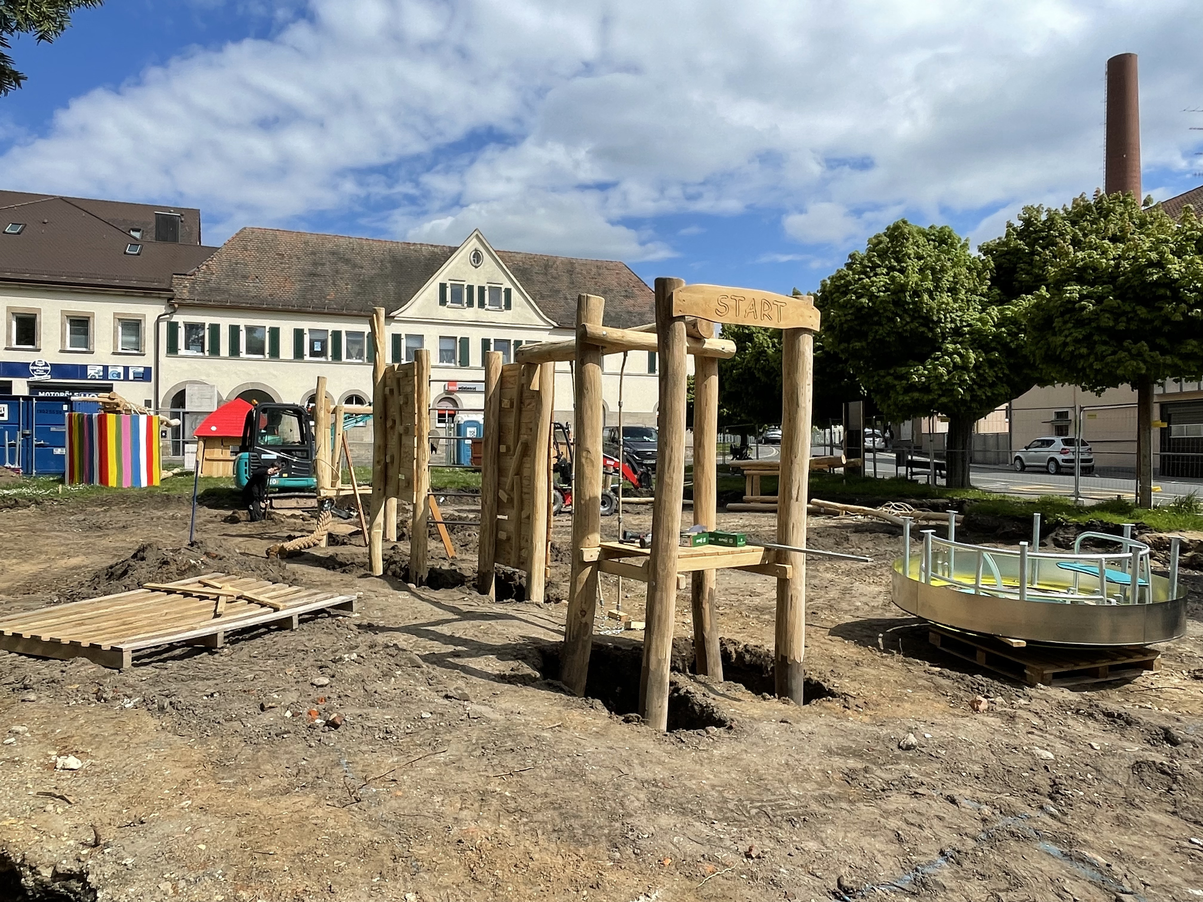 Aufbau von Spielgeräte mit grißem Holzanteil auf einem Spielplatz.